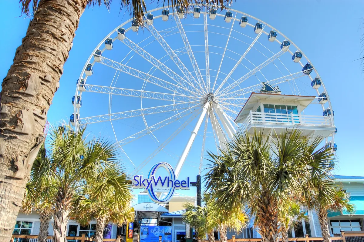 This image features the iconic SkyWheel, framed by palm trees and entrance signage, evoking a sense of excitement and adventure. The bright, open setting hints at the array of nearby entertainment and memorable experiences awaiting guests.