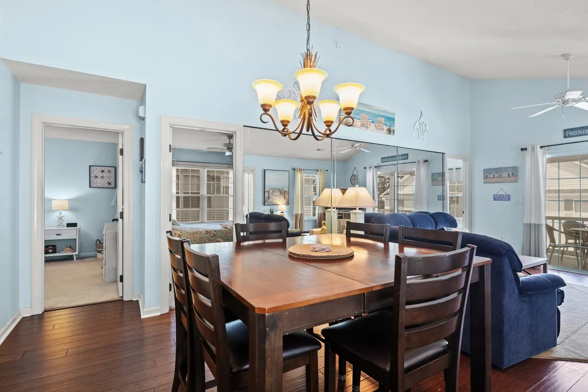 A cozy dining area takes center stage here, with a well-appointed dining table under a chandelier, adjacent to a sofa and decorated walls. The layout encourages intimate meals, festive gatherings, or spirited game nights, embodying the multifunctional aspect of the open-concept area.